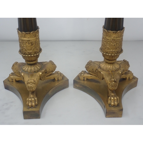 478 - A pair of French Empire Candlesticks in ormolu and bronze, with classical mouldings, plain bronze fl... 