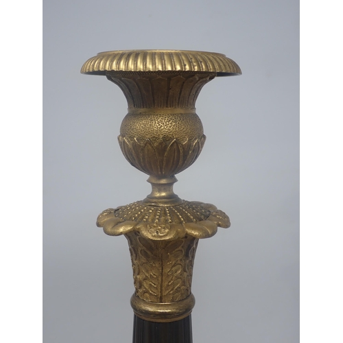 478 - A pair of French Empire Candlesticks in ormolu and bronze, with classical mouldings, plain bronze fl... 