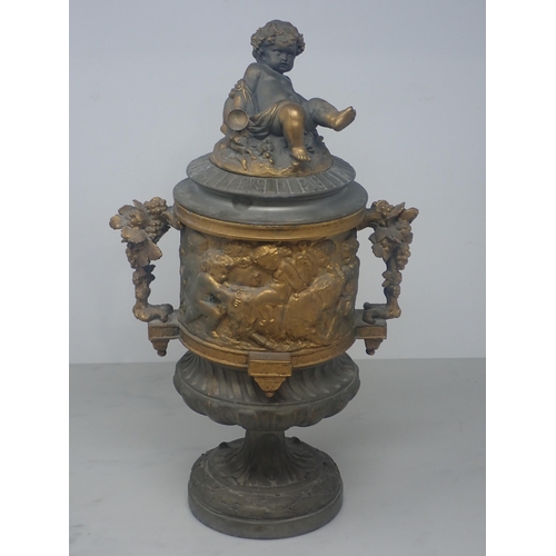 484 - A cast metal Urn, partially gilt with cherub surmount to the cover and a frieze of cherubs in variou... 