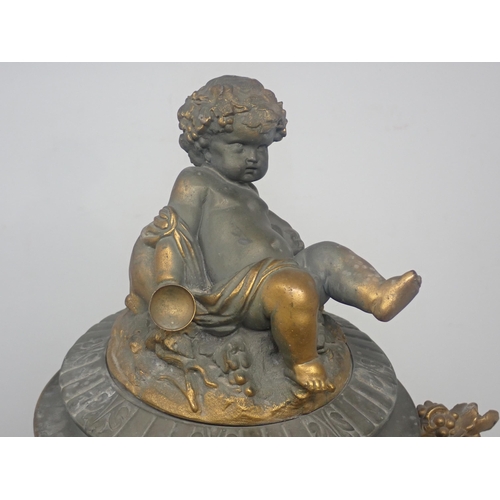 484 - A cast metal Urn, partially gilt with cherub surmount to the cover and a frieze of cherubs in variou... 