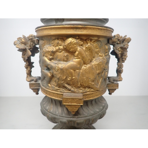 484 - A cast metal Urn, partially gilt with cherub surmount to the cover and a frieze of cherubs in variou... 