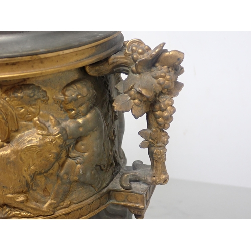 484 - A cast metal Urn, partially gilt with cherub surmount to the cover and a frieze of cherubs in variou... 