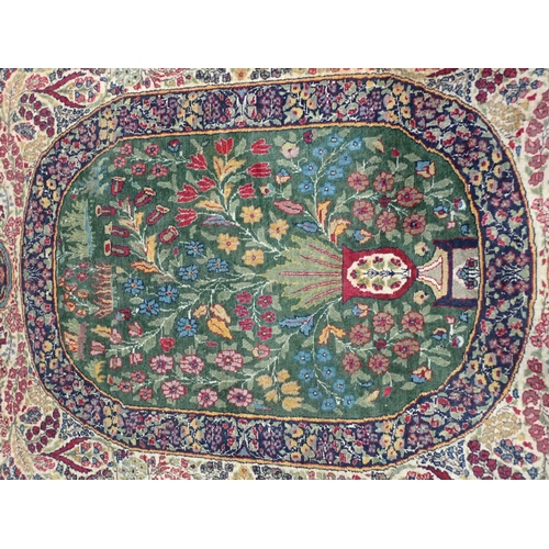 500 - A fine quality Persian Rug with floral designs two the borders, and central oval depicting vase of f... 