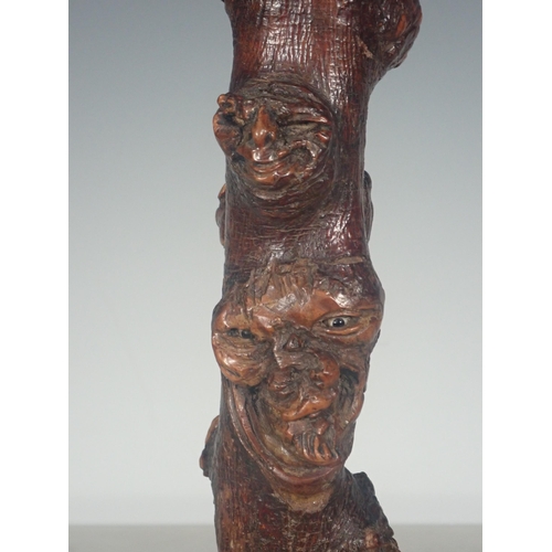 589 - A burr wood Stick carved grotesque masks on a marble plinth, 16½in H overall