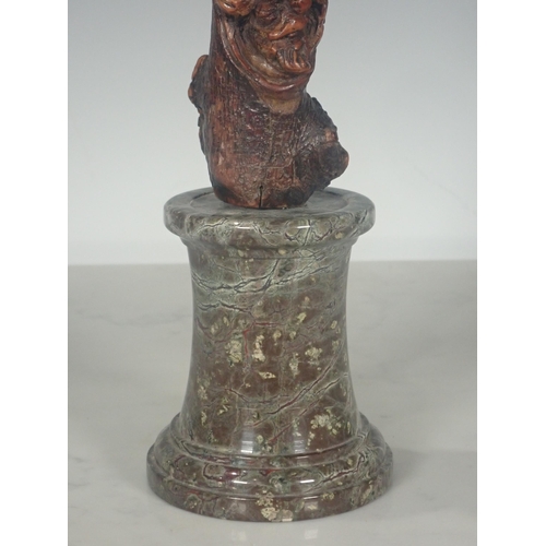 589 - A burr wood Stick carved grotesque masks on a marble plinth, 16½in H overall