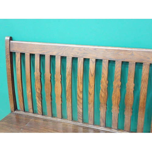 634 - An oak Hall Bench with shaped and straight bars to the back, solid seat on baluster turned front sup... 