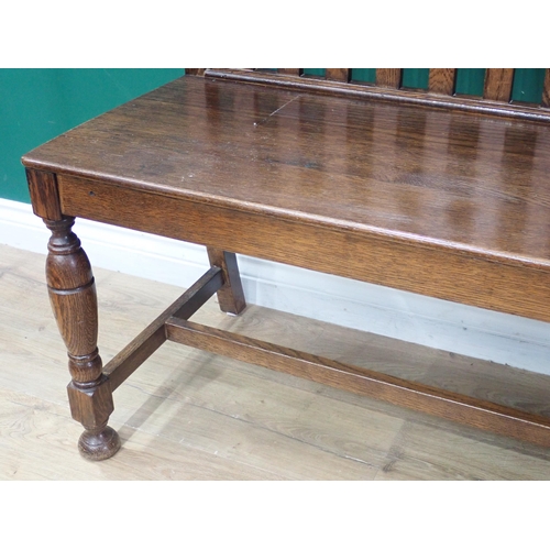 634 - An oak Hall Bench with shaped and straight bars to the back, solid seat on baluster turned front sup... 