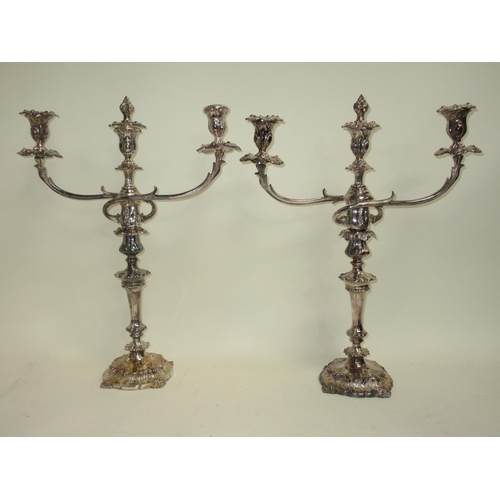 79 - A pair of plated two branch three light Candlesticks with foliate bands on shaped circular bases, 21... 