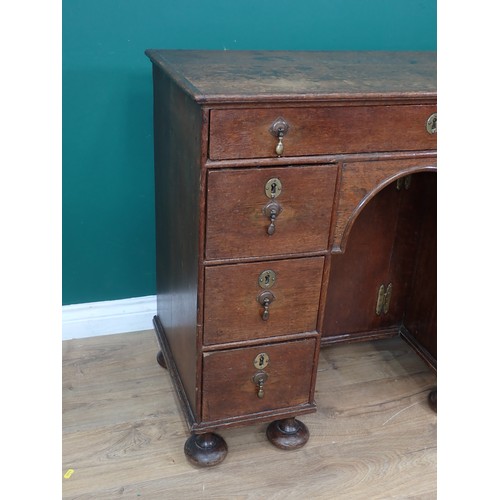 637 - An 18th Century oak Kneehole Desk, the arched recess with cupboard surrounded by seven drawers, on l... 