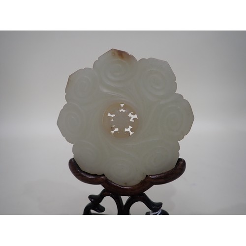 412 - A Chinese celadon Jade Bi Disk carved flower head with geometric carved centre section on hardwood s... 