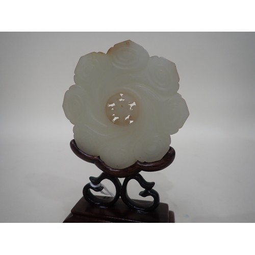 412 - A Chinese celadon Jade Bi Disk carved flower head with geometric carved centre section on hardwood s... 