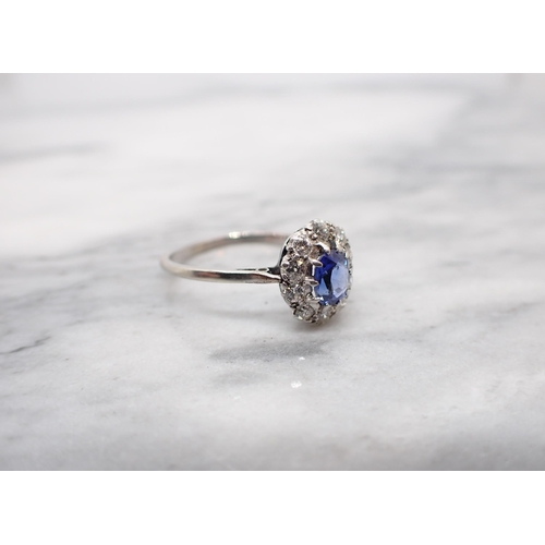 157 - A Sapphire and Diamond Cluster Ring claw-set oval-cut sapphire within a frame of ten brilliant-cut d... 