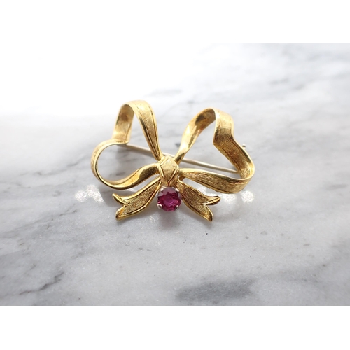 158 - An 18ct gold Ribbon Bow Brooch claw-set round ruby, approx 4.90gms