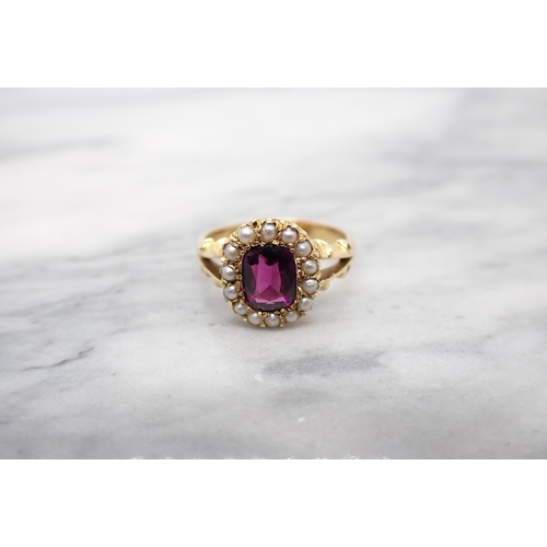 175 - A Garnet and Seed Pearl cluster Ring pavé-set cushion-cut garnet within a frame of seed pearls in 18... 