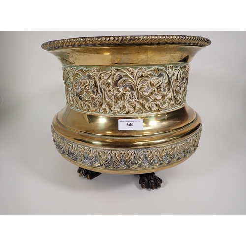 68 - A circular brass Jardiniere with gadroon rim, floral scroll and leafage embossed friezes on paw feet... 