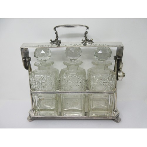 106 - A silver plated Tantalus fitted three square cut glass Decanters and Stoppers, reeded rim on ball fe... 