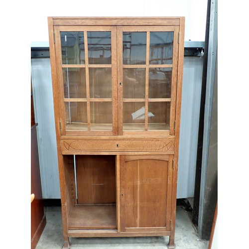 384 - An Arts and Crafts oak Cabinet with pair of glazed panelled doors above an inlaid frieze drawer with... 