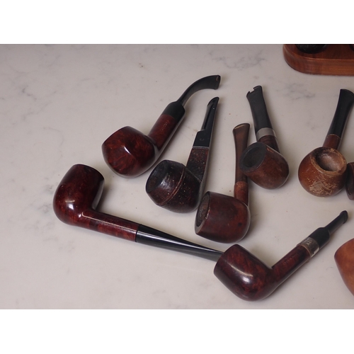 107 - A bundle of 12 briar pipes, some with white metal collars, and a 2 bay pipe stand