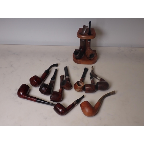 107 - A bundle of 12 briar pipes, some with white metal collars, and a 2 bay pipe stand