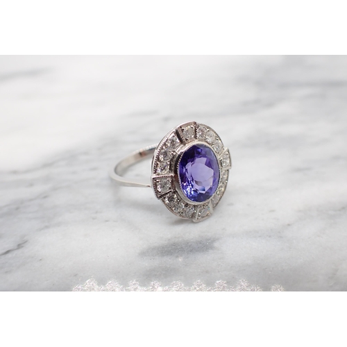 187 - A Tanzanite and Diamond Cluster Ring millegrain-set oval-cut tanzanite within a frame of brilliant-c... 