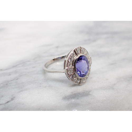 187 - A Tanzanite and Diamond Cluster Ring millegrain-set oval-cut tanzanite within a frame of brilliant-c... 