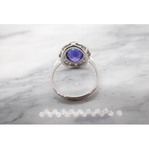 187 - A Tanzanite and Diamond Cluster Ring millegrain-set oval-cut tanzanite within a frame of brilliant-c... 