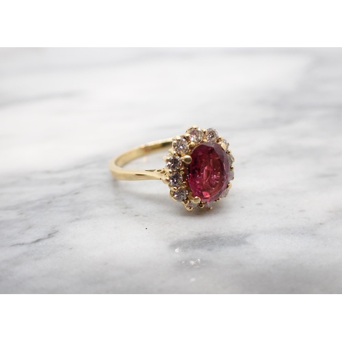 190 - A Pink Tourmaline and Diamond Cluster Ring claw-set oval-cut tourmaline within a frame of twelve bri... 