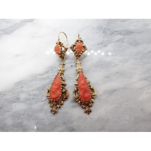 204 - A pair of carved Coral Cameo Ear Pendants each within intricate yellow metal mount