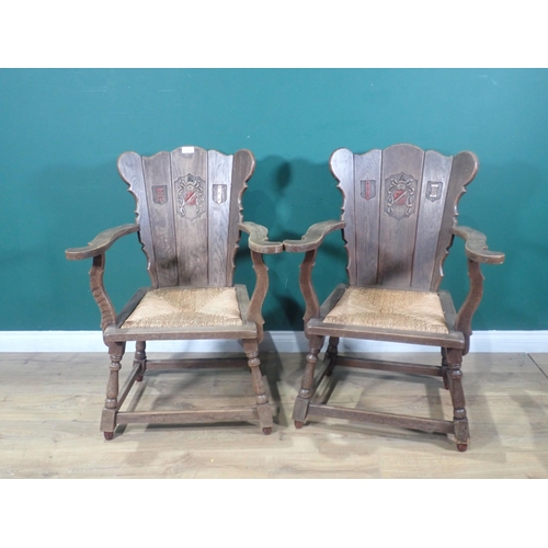 375 - A pair of oak Armchairs with plank backs carved Armorial Crests with rush seats on turned supports u... 