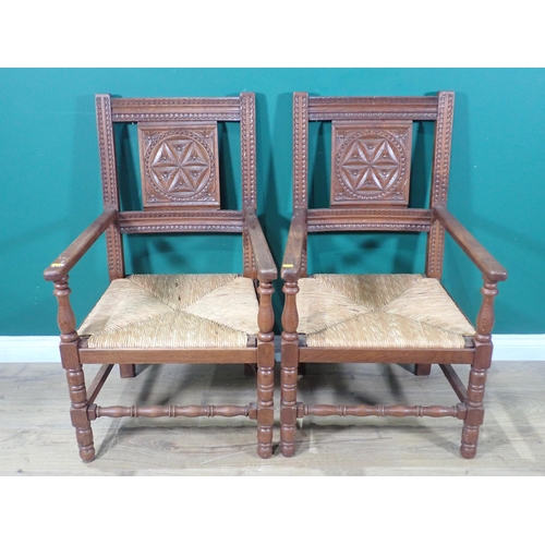 5 - A pair of oak Elbow Chairs with roundel carved splat backs with rush seats and mounted upon tuned su... 