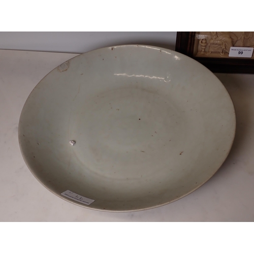 99 - A large Oriental shallow Bowl with celadon glaze, 14in, A/F, and a framed resin Panel of religious s... 