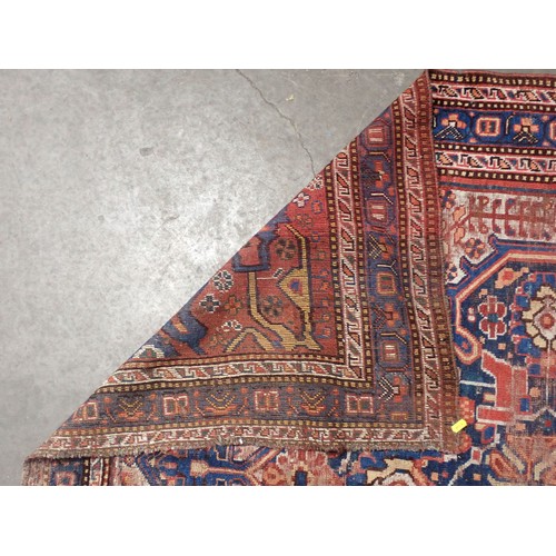 111 - A red ground Persian Rug with stylised floral design on blue medallion 6ft 1in L x 4ft 11in W