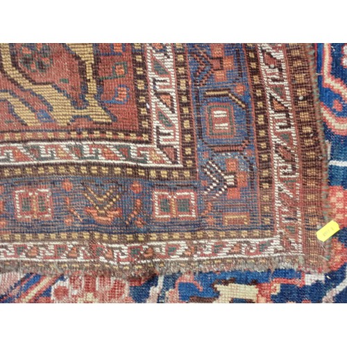 111 - A red ground Persian Rug with stylised floral design on blue medallion 6ft 1in L x 4ft 11in W