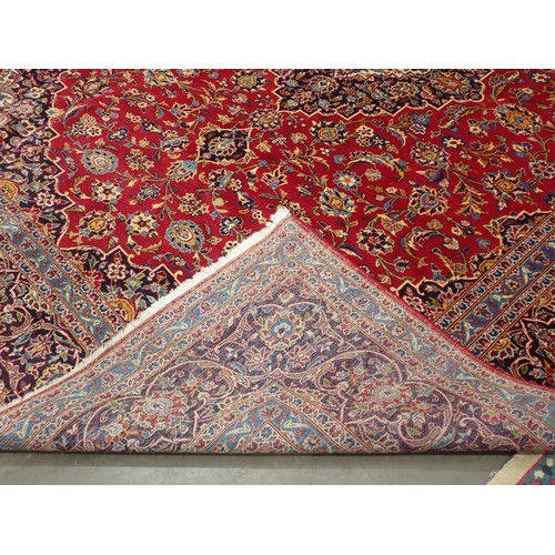 497 - A large Persian style Carpet with multiple borders and central floral medallion on a red ground, 13f... 