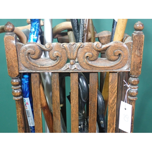 80 - An oak Stick Stand with leafage scroll frieze together with a quantity of Walking Sticks and Umbrell... 