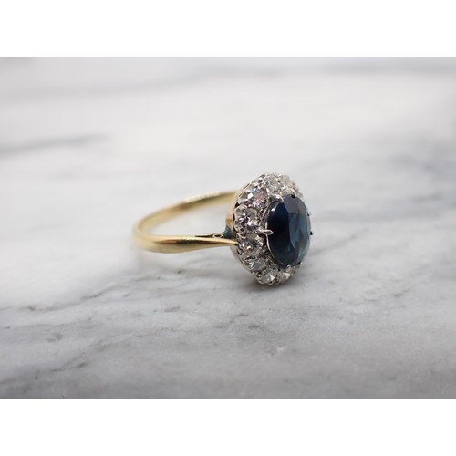 164 - A Sapphire and Diamond Cluster Ring claw-set oval-cut sapphire within a frame of twelve old and bril... 