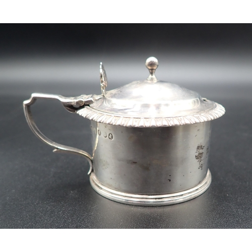 102 - A Georgian silver drum Mustard Pot, engraved crest, gadroon rim, ornate thumb piece, London hallmark... 