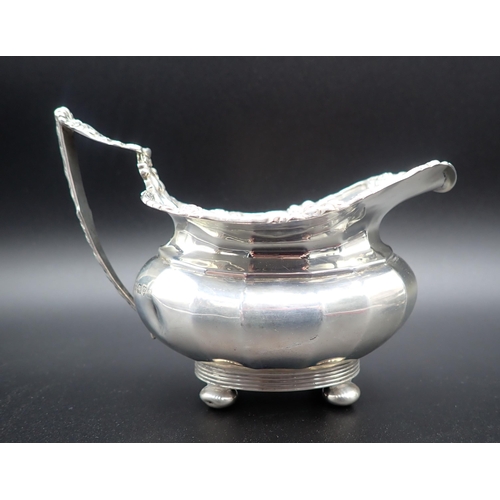 103 - A George V silver two-handled Sugar Bowl and Milk Jug of panelled form with floral scroll borders an... 