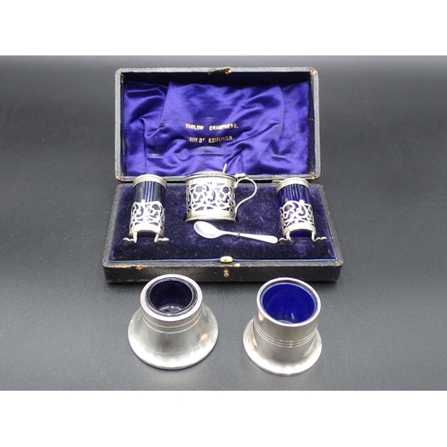 128 - An Edward VII silver three piece Condiment Set of pierced circular form, having blue glass liners, B... 