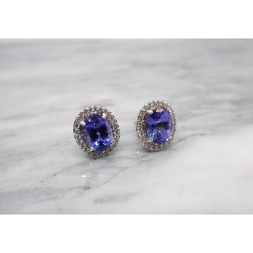 165 - A pair of Tanzanite and Diamond Cluster Earrings each claw-set oval-cut tanzanite within a frame of ... 