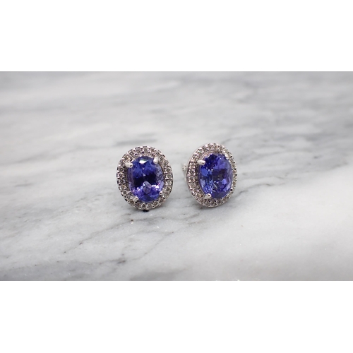 165 - A pair of Tanzanite and Diamond Cluster Earrings each claw-set oval-cut tanzanite within a frame of ... 