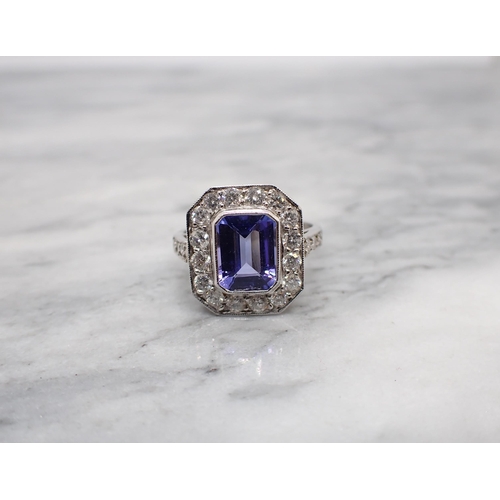 175 - An Art Deco style Tanzanite and Diamond Cluster Ring millegrain-set step-cut tanzanite within a fram... 