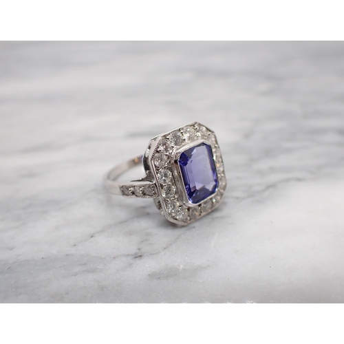 175 - An Art Deco style Tanzanite and Diamond Cluster Ring millegrain-set step-cut tanzanite within a fram... 