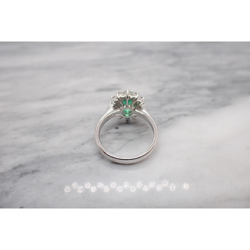 178 - An Emerald and Diamond Cluster Ring claw-set oval-cut emerald within a frame of twelve brilliant-cut... 