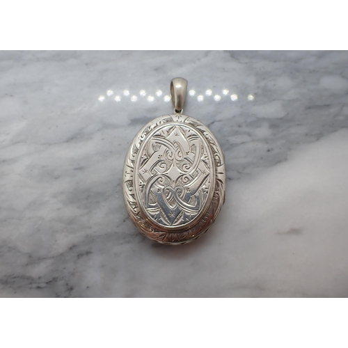 204 - An unmarked oval white metal Locket with bright-cut engraved decoration