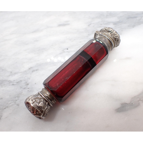 210 - A Victorian double ended ruby glass Scent Bottle with embossed white metal lids to each end, 3in lon... 