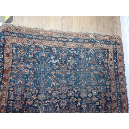 10 - An old Persian woollen Rug with stylised flower design on blue ground within multiple borders 6ft 2i... 