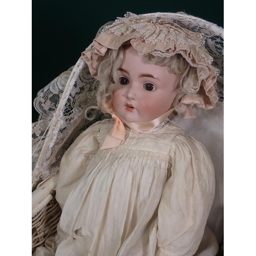 67 - A German Bisque headed Doll and a reproduction wicker Pram.