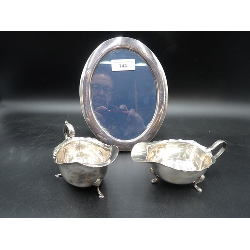 144 - A modern silver oval Photograph Frame, Sheffield 1987, 8 x 7in, and two silver Sauce Boats