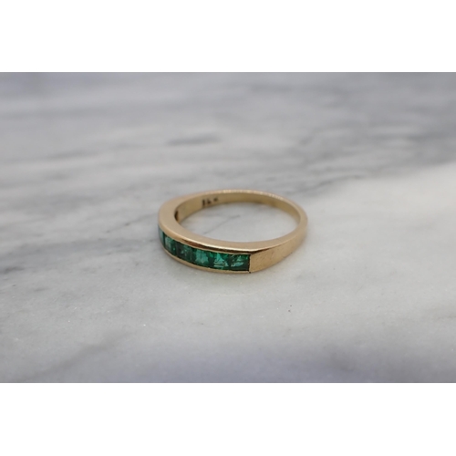 168 - An Emerald half Eternity Ring channel-set calibré-cut stones, stamped 18K, ring size N